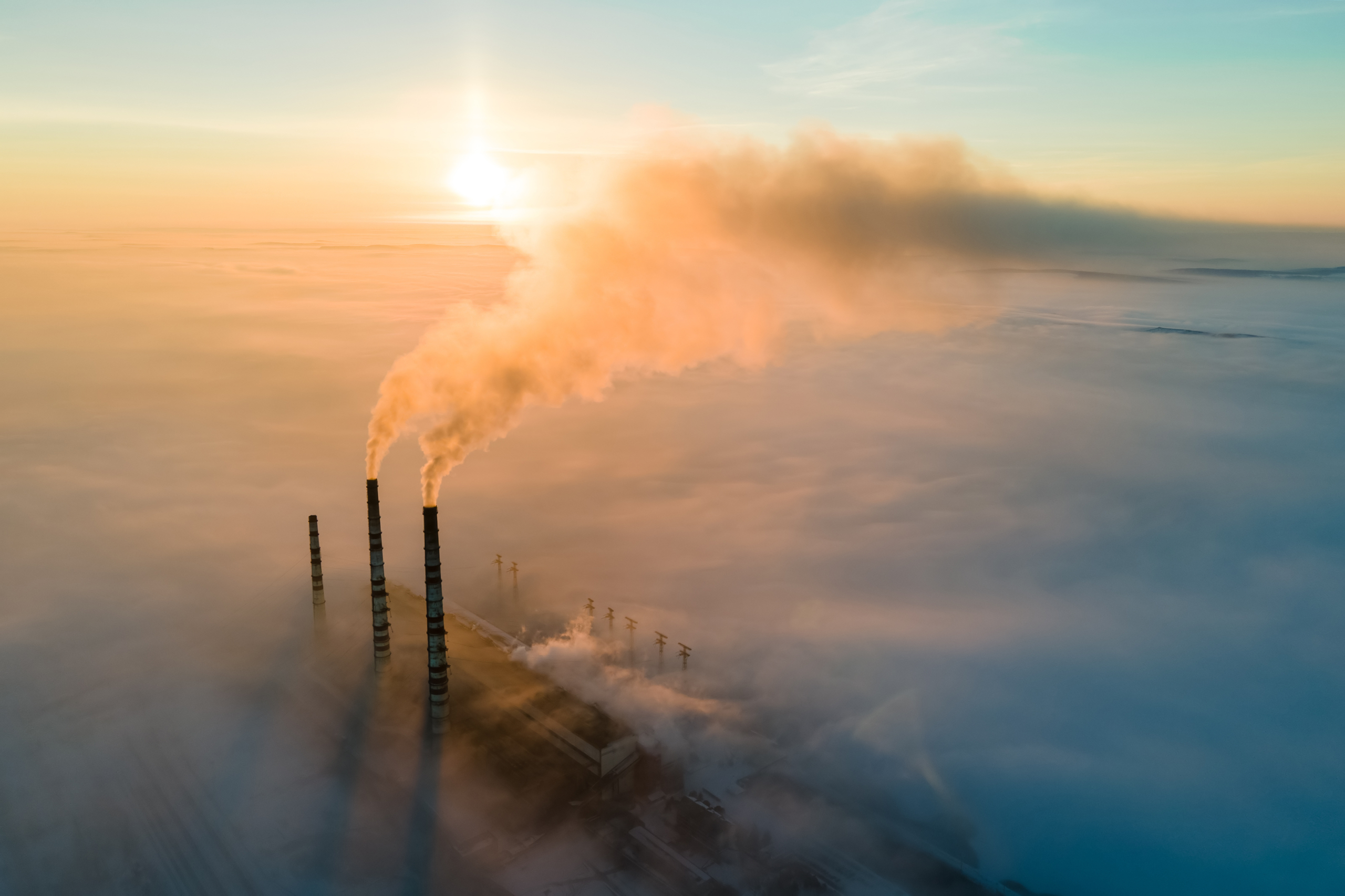 Factory chimneys rising above clouds – sunrise
